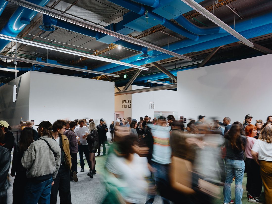 Au niveau 2 du Centre Pompidou, la foule circule dans une ambiance vivante et curieuse pendant "Because Beaubourg". Sous le plafond industriel marqué par les tuyaux bleus emblématiques, les visiteurs échangent, explorent, discutent. Devant la librairie-boutique, le flux constant crée une atmosphère dynamique, entre rendez-vous culturels et instants spontanés. Le lieu devient un point de rencontre vibrant entre art, idées et public.