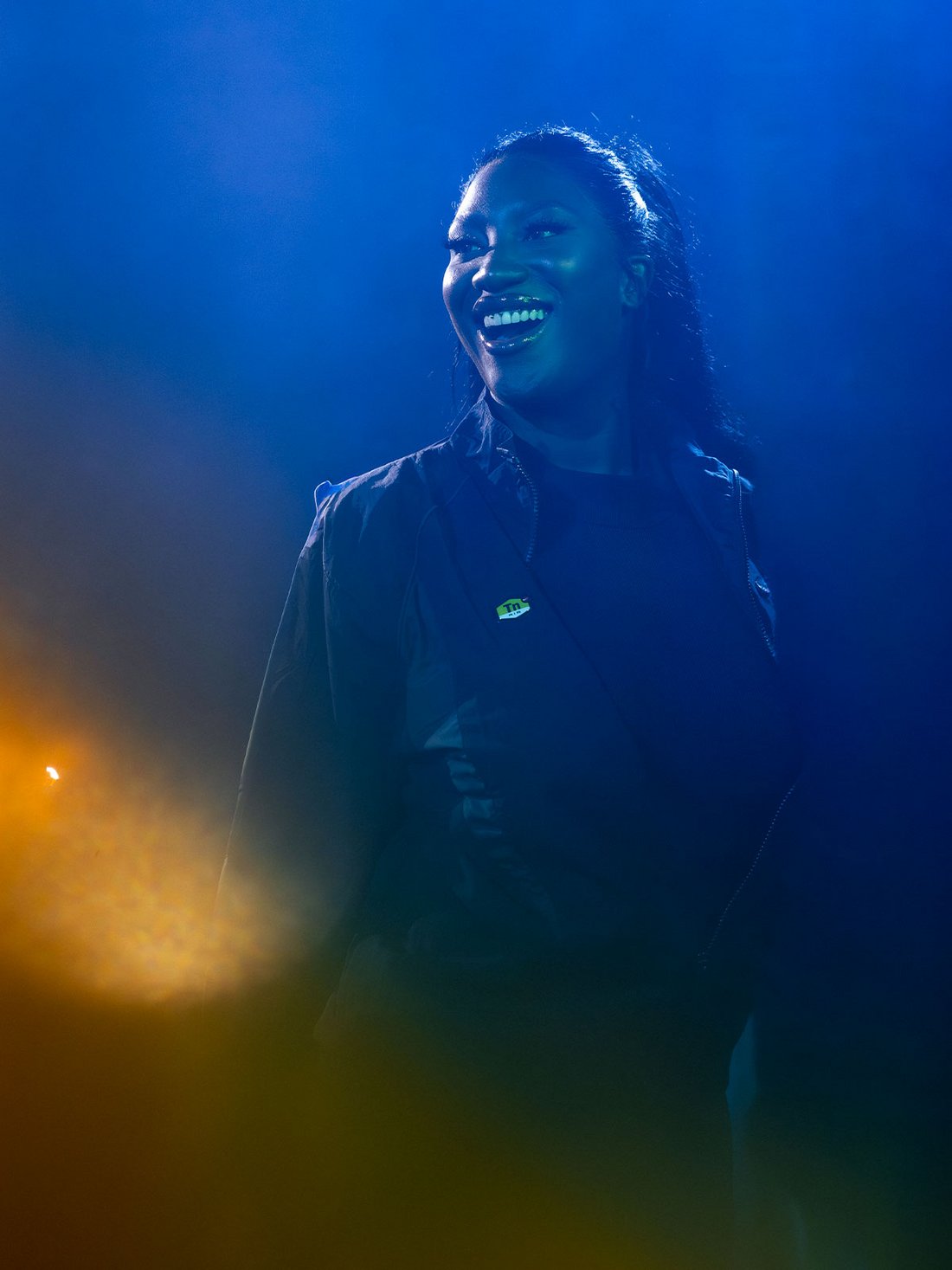 Sous les lumières bleues et les halos dorés de la soirée "Because Beaubourg", Aya Nakamura rayonne sur scène. Son sourire éclatant traduit l’énergie et la complicité partagée avec le public. Vêtue de noir, elle incarne la puissance et la modernité de la scène musicale actuelle. L’éclairage soigné crée une aura presque cinématographique, sublimant sa présence magnétique dans ce haut lieu culturel parisien.
