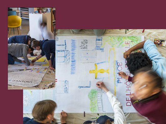 Enfants en train de dessiner une carte sur une grande feuille de papier au sol
