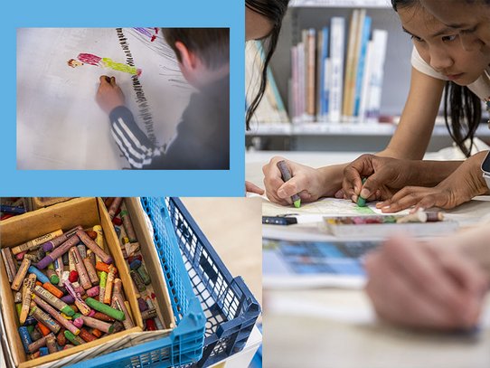 Dans une salle de classe lumineuse, plusieurs élèves concentrés participent à un atelier artistique. Au premier plan, des mains tiennent des pastels et tracent des formes colorées sur du papier. Une caisse remplie de crayons multicolores souligne la créativité et le travail manuel. L’ambiance est studieuse et collaborative, typique d’un cours d’arts plastiques au collège.